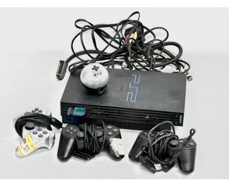 A PS2 (PlayStation 2) console with 3 controllers. 