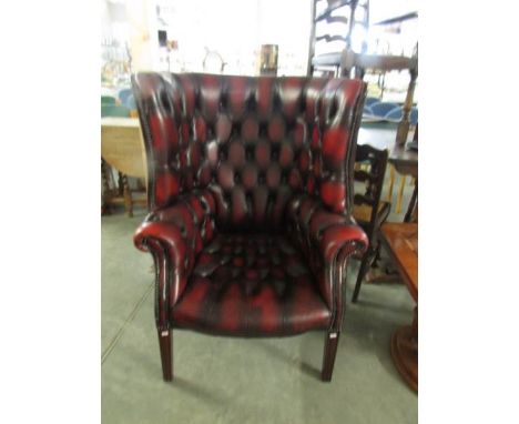 A deep button back maroon leather library wing back chair
