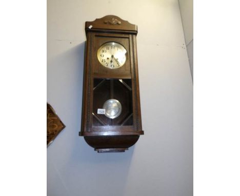 An Edwardian oak pendulum wall clock in working order