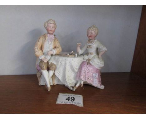 A German bisque porcelain nodding head group of lady and gentleman playing chess (ladies hand is missing)