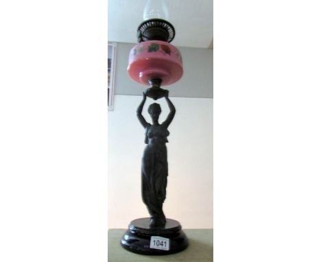 A Victorian oil lamp supported by a spelter figure and with a pink glass font, complete with chimney