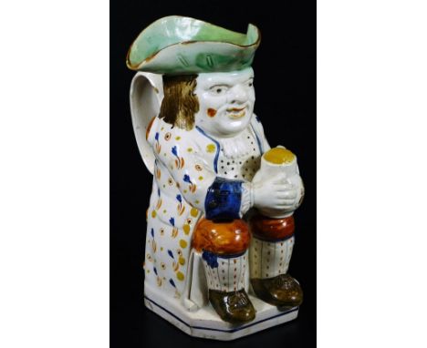 An early 19thC Prattware Toby jug, the toper sat in floral jacket picked out in yellow, holding a jug, aside pipe, with green
