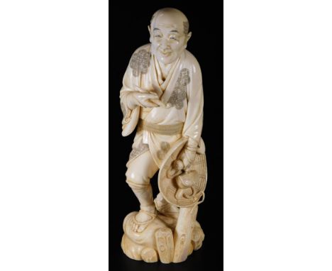 A Japanese Masayuki Meiji period ivory okimono figure, of a gentleman in flowing robes holding pipe and hat, on a naturalisti