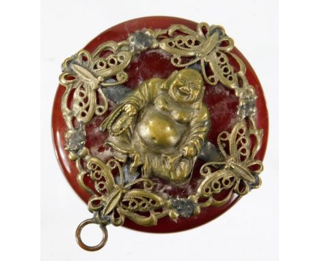 An early 20thC Chinese pendant, on a polished stone ground, raised with a figure of Buddha, surrounded by pierced flowers and