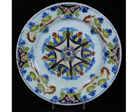 An 18thC English Delft pottery plate, of circular form, polychrome decorated with flowers in a geometric centre, predominatel