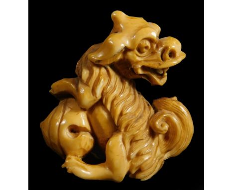 A 19thC ivory netsuke, in the form of a Shishi with a nut, signed, 4cm H.