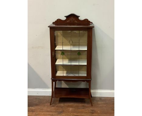 An Edwardian display cabinet with raised hand painted floral back, stained glass single door encasing a 2 shelved area on tap