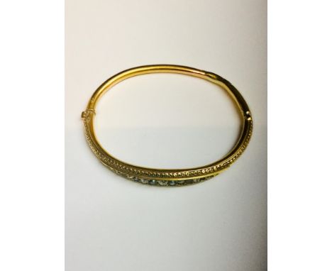 A 15ct gold Edwardian bangle set with 7 x round brilliant cut diamonds and 8 x small black pearls in a graduated channel sett