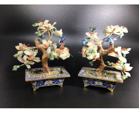 A pair of Oriental cloisonné enamel and hard stone bonsai trees with red, white and green blossom and a pair of blue birds on