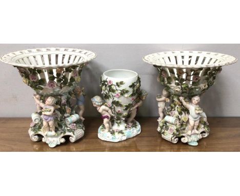 A pair of Sitzendorf figural porcelain comports with pierced bowls, the base with three cherubs and all over floral and folia