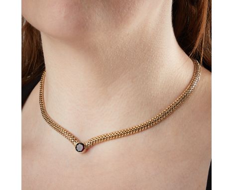 Zelman &amp; Friedman, United States. 14k yellow gold domed woven link V-shaped necklace with a solitaire garnet. The round-c