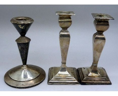 A pair of silver candlesticks, a/f, and one other silver candlestick, height of pair 12.5cm