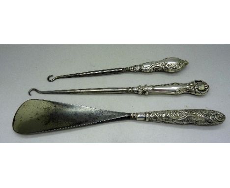Two silver handled button hooks and a shoe horn
