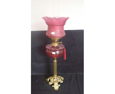 A 19TH CENTURY BRASS TABLE OIL LAMP with pink glass reservoir, on fluted column and cast splayed foot, with etched pink glass