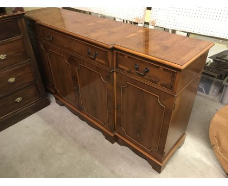 A modern yew wood and cross banded break front sideboard with central long drawer over two cupboard doors flanked by short dr