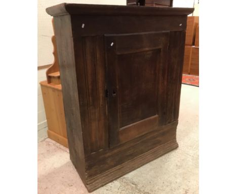 A 17th Century Dutch oak cupboard, the plain moulded cornice over a single panelled door enclosing a shelf, flanked by moulde