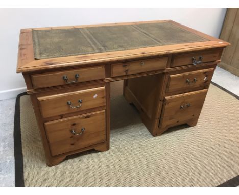 A modern pitch pine double pedestal desk, the top with tooled and gilded leather insert and moulded edge over three frieze dr