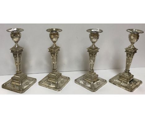 A pair of late Victorian silver sheathed table candlesticks with embossed ram's head, ribbon and urn decoration in the Adam R