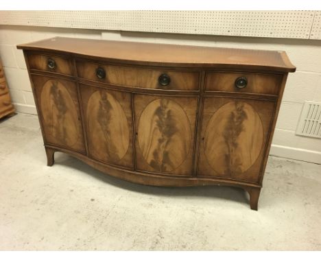 A Bevan Funnell Reprodux serpentine fronted sideboard in the George III manner with three drawers over four cupboard doors on
