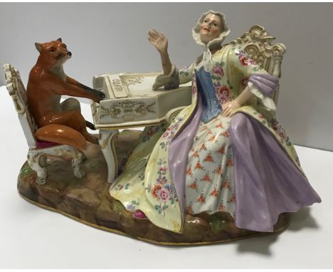 A 19th Century Meissen figure group as a fox playing the piano, a lady in floral dress seated listening on, bearing blue cros