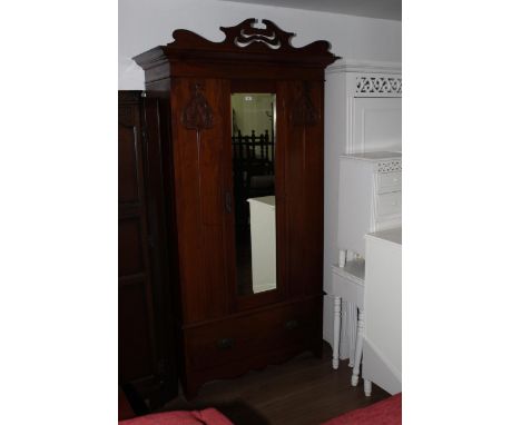 An Edwardian mahogany mirror door wardrobe, bearing label to interior manufactured by CWS, having a shaped and pierced surmou