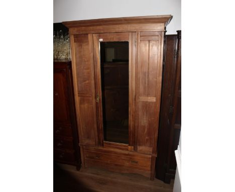 An Edwardian single mirror door wardrobe, having a moulded cornice and plain frieze above the central rectangular mirror door