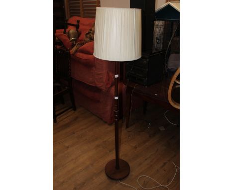 A mid century teak standard lamp of turned cylindrical form, with circular base and cream material shade. Height 31.5 cm. CON