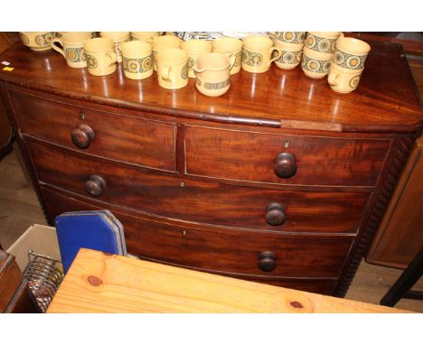 A late Georgian figured mahogany bow front chest of drawers with spiral turned quartered columns, fitted with two short and t