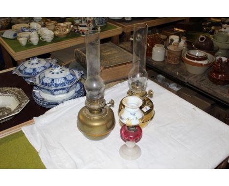 Two brass table oil lamps with chimneys, each 45 cm high including the chimneys, with a 19th century cranberry and milk glass