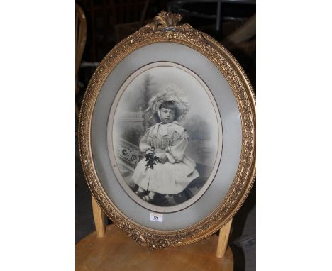 A late Victorian photographic print, portrait of a seated girl, oval 36 cm x 30 cm in gilt moulded frame. CONDITION REPORT: T
