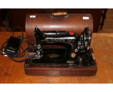 A vintage electric singer sewing machine housed in a traditional walnut domed case with carry handle.  30 x 44 x 19 cm. CONDI