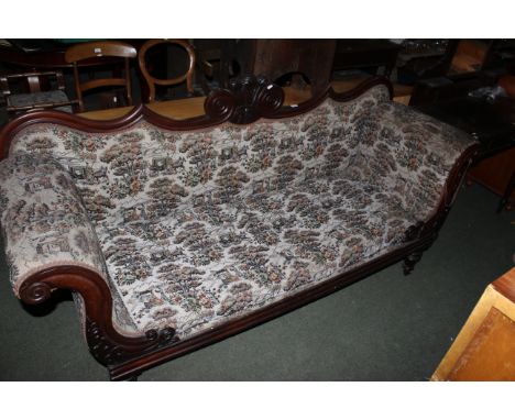 A Victorian mahogany show wood framed settee with fleur de lys cresting, scrolled arms on turned legs and castors, upholstere