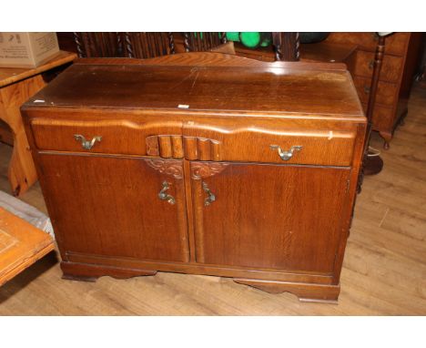 A 1930's oak sideboard with moulded rectangular top above two shaped drawers and cupboard doors below, all raised on shaped b