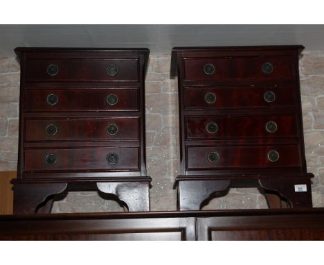 A pair of reproduction mahogany bedside chests, having moulded rectangular tops above four cockbeaded drawers with shaped and