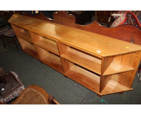 A modern pine low bookcase or storage unit of oblong form with canted ends and enclosing 10 divisions, raised on block feet. 