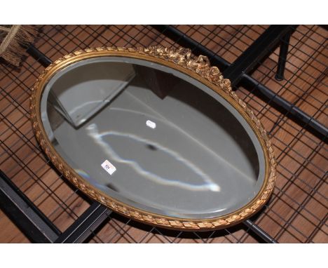 A vintage oval gilt framed mirror with ribbon and foliate crest, the bevelled plate enclosed by a rope twist and reeded frame