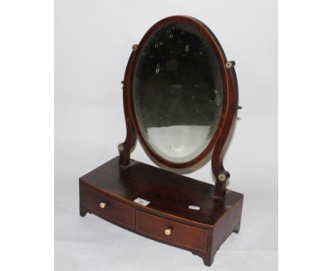 A George III mahogany toilet mirror with central oval bevelled plate between shaped uprights, the bowed base with two drawers