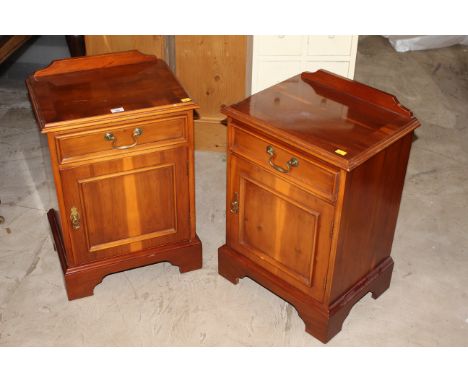 A pair of reproduction yew wood bedside cabinets, each with shallow raised back above a moulded quarter veneered top, with si
