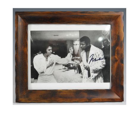 A remarkable black-and-white photograph capturing Muhammad Ali and Elvis Presley, two of the most iconic figures in sports an
