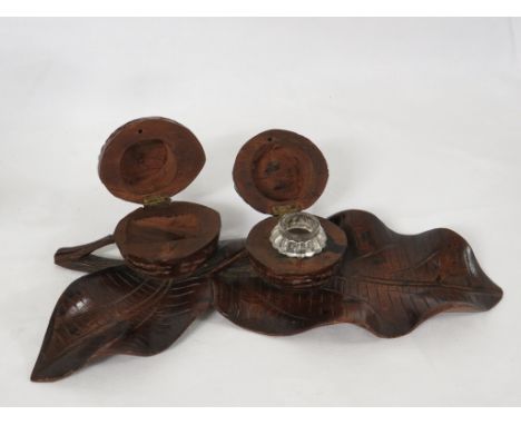 A wooden inkwell carved as a leaf and two nuts, one with a clear glass insert, length 25cm