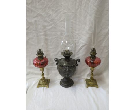 Pair of small brass oil lamps on foliate moulded brass baluster columns on square bases with cranberry glass reservoirs, thum