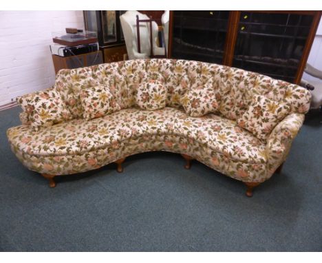 An early 20th century curved button back sofa with cabriole legs and scallop shell to the shoulder, with stylistic floral pat