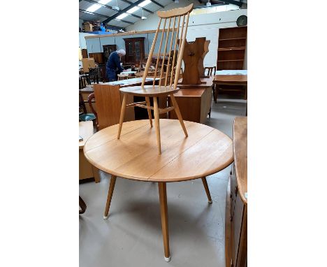 An Ercol light oak dining suite comprising table with circular drop leaf top and 4 stick back chairs 