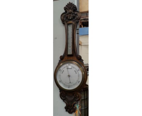 An Edwardian aneroid barometer in carved oak case 
