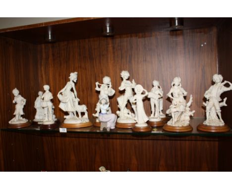 A NAO FIGURE OF A YOUNG GIRL HOLDING A PUPPY TOGETHER WITH A COLLECTION OF MODERN RESIN FIGURES ON WOODEN PLINTHS (12)
