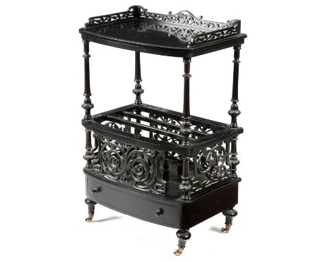 A Victorian ebonised Canterbury, with pierced scrolling fretwork decoration, the raised top with three quarter gallery above 