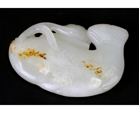 A Chines jade figure in the form of a fish with a lily pad, on an associated hardwood stand, 6.5cms (2.5ins) wide.