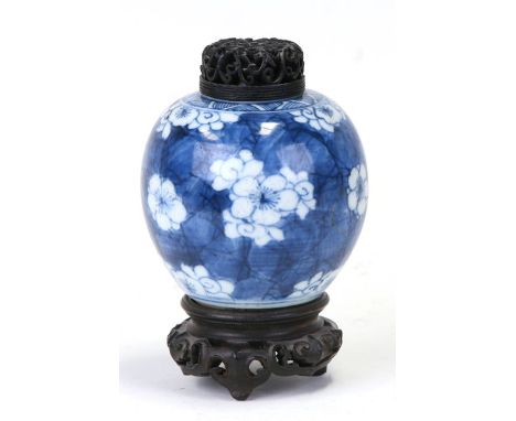 A Chinese blue & white ginger jar of small proportions decorated with prunus, with pierced wooden cover, on a hardwood stand,