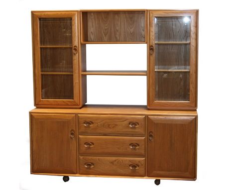 An Ercol Windsor display wall unit, the upper section with two open bookshelves flanked by two glazed cabinets above a base w