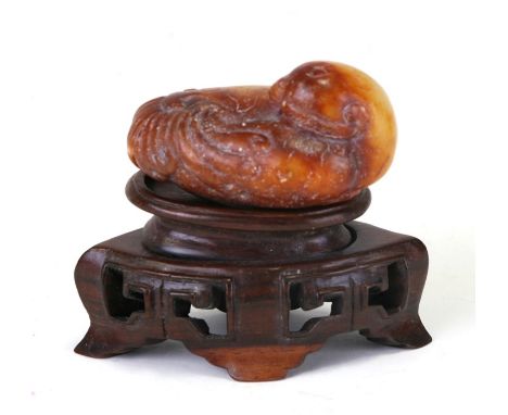 A Chinese russet jade figure of a quail mounted on a hardwood stand, 5.5cms (2.25ins) long.